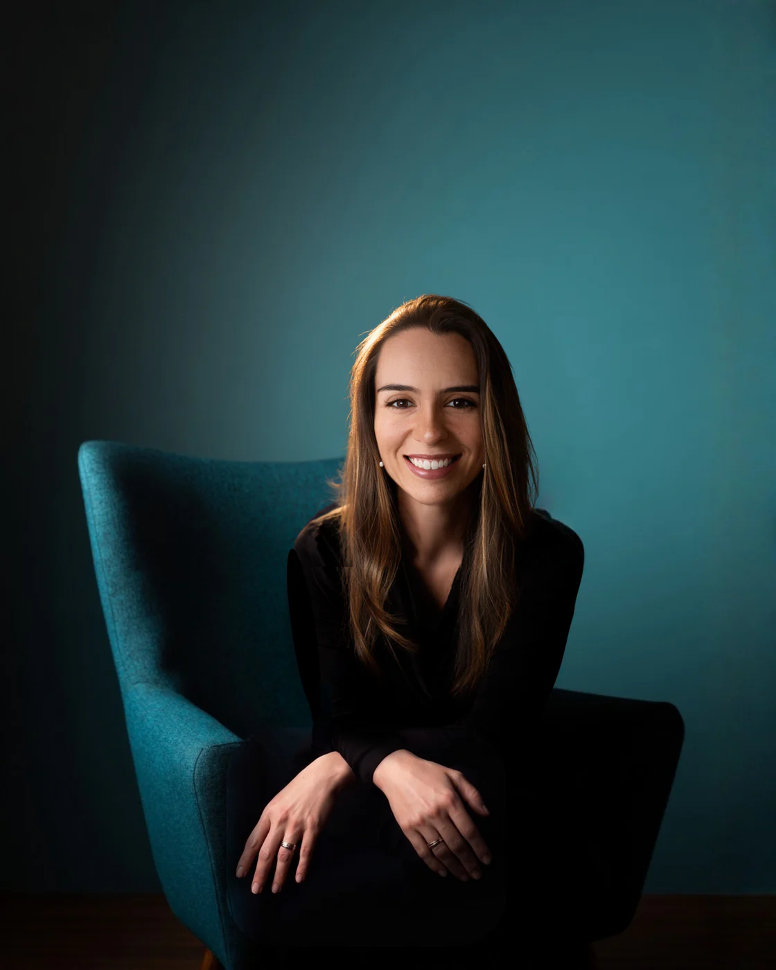 Bárbara Zomer, fundadora da Lightsoul, sentada numa poltrona turquesa